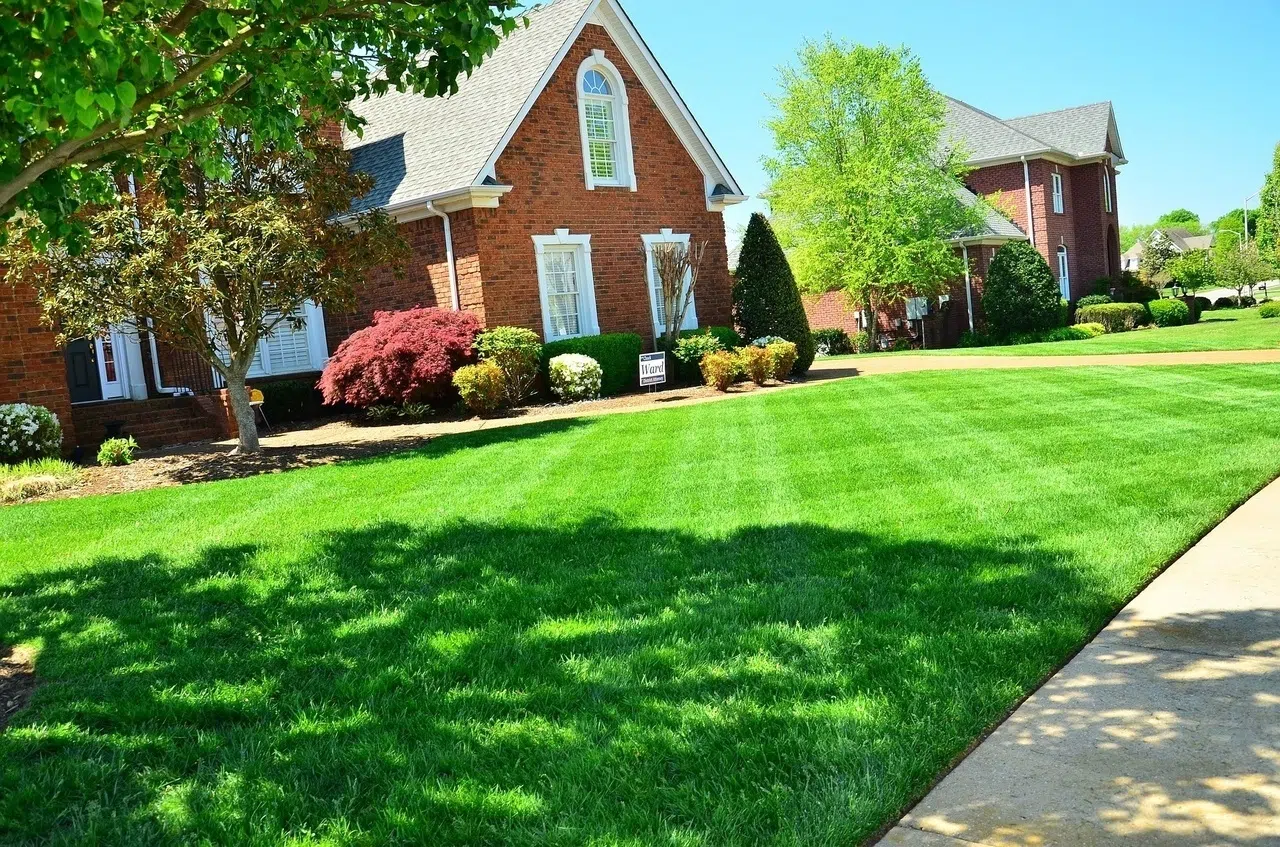 Freshly mowed striped lawn beside a red brick house — Cutting Edge Lawn Care in Washington