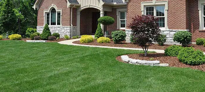 Manicured lawn and mulch beds at a brick home entrance — Cutting Edge Lawn Care in Washington